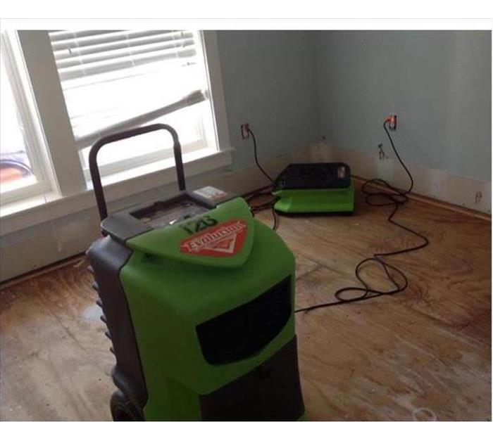 A dehumidifier and an air mover placed inside a room