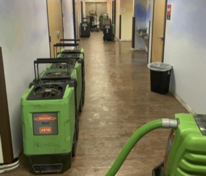 Hallway in a school with various pieces of SERVPRO fans and dehumidifiers